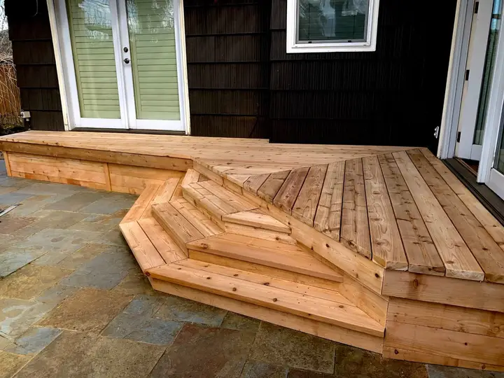 Cedar deck with angled steps leading down to a stone patio