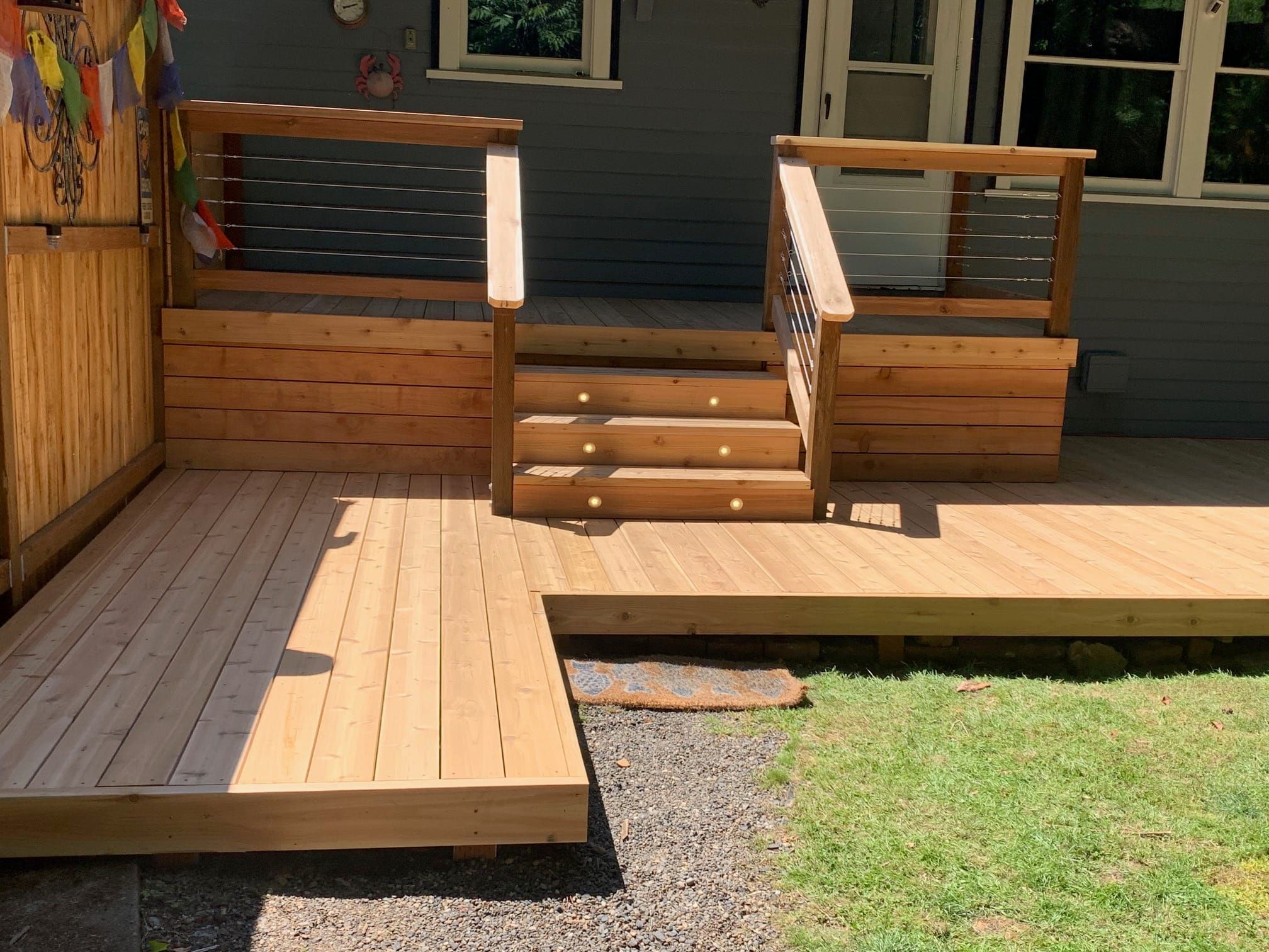 Low cedar entry deck with stainless-steel cable railings and wide central steps
