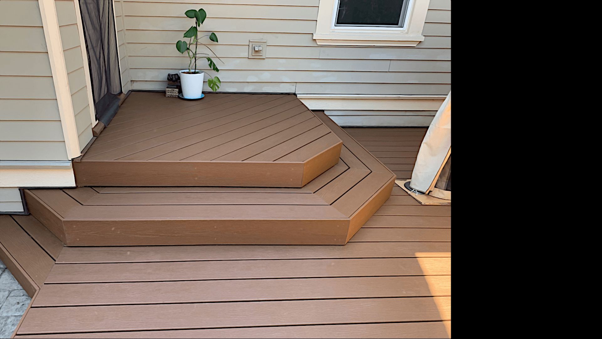 Angled composite entry steps leading from a back door to a custom brown deck